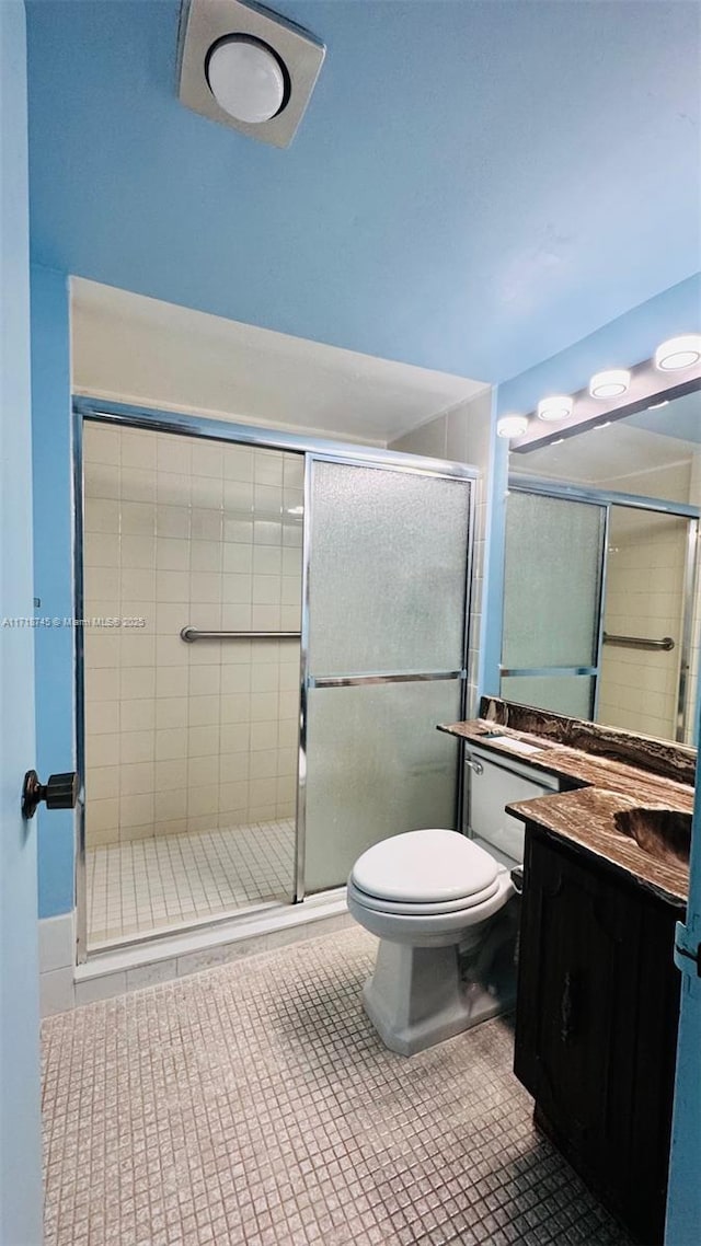 bathroom with tile patterned flooring, vanity, toilet, and an enclosed shower