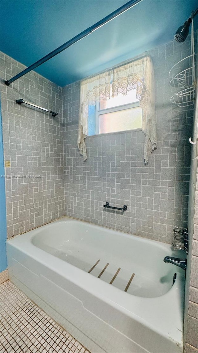 bathroom with tile patterned flooring and washtub / shower combination