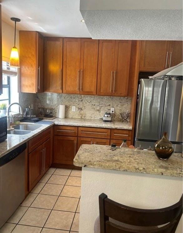 kitchen featuring light stone countertops, sink, stainless steel appliances, decorative light fixtures, and decorative backsplash