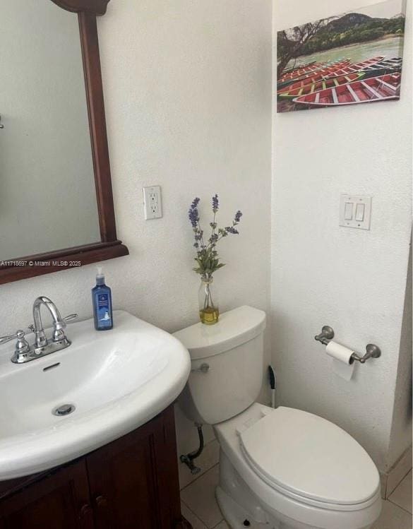 bathroom with toilet, vanity, and tile patterned floors