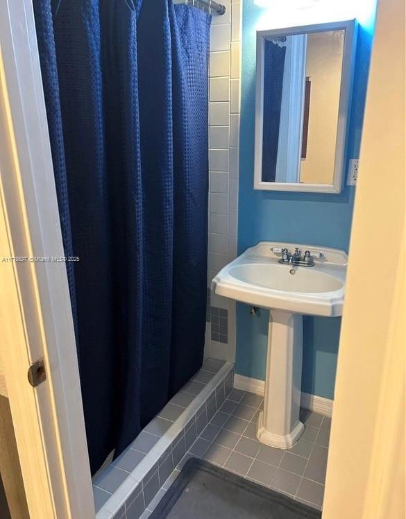 bathroom with a shower with shower curtain and tile patterned flooring