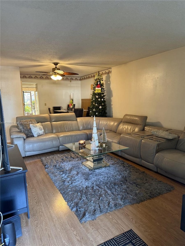 living room featuring a textured ceiling, hardwood / wood-style flooring, and ceiling fan