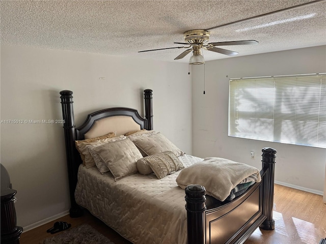 bedroom with ceiling fan, light hardwood / wood-style floors, and a textured ceiling