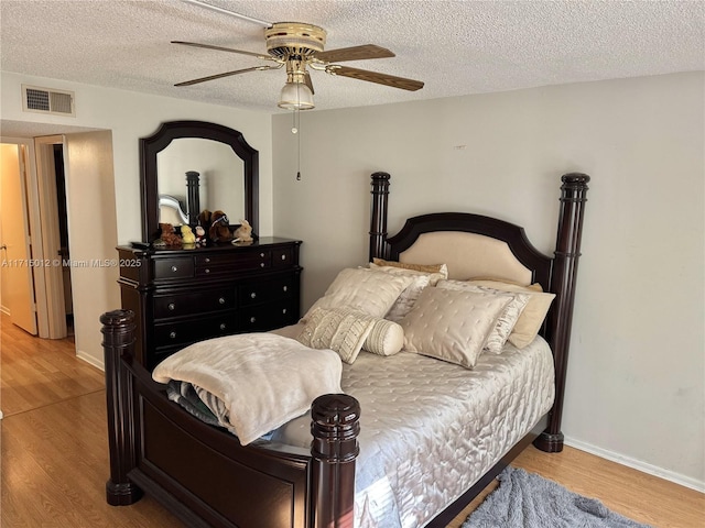 bedroom with a textured ceiling, light hardwood / wood-style flooring, and ceiling fan