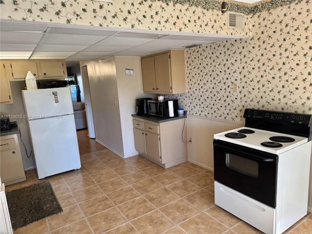 kitchen featuring a paneled ceiling, cream cabinets, light tile patterned floors, and white appliances