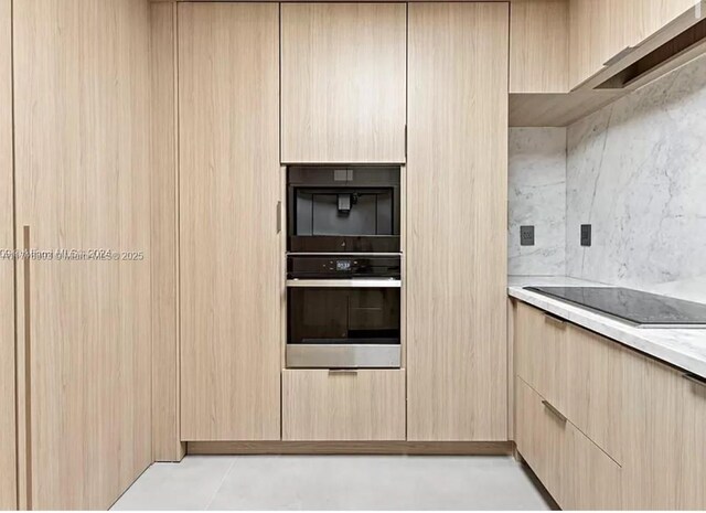 kitchen featuring light stone countertops, light brown cabinets, double wall oven, and black electric stovetop