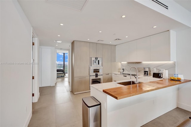 kitchen featuring tasteful backsplash, kitchen peninsula, sink, and a breakfast bar