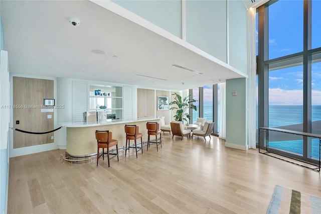 bar featuring light hardwood / wood-style floors, a water view, and a wall of windows