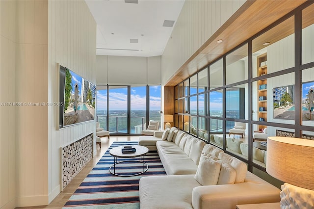 living room featuring hardwood / wood-style floors, a towering ceiling, and a wall of windows