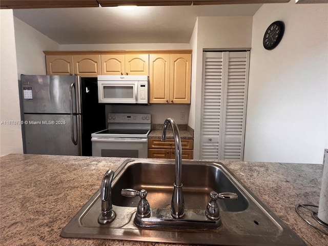 kitchen featuring light brown cabinetry, white appliances, and sink