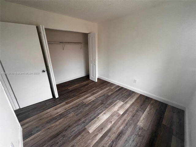 unfurnished bedroom featuring dark hardwood / wood-style floors, a textured ceiling, and a closet