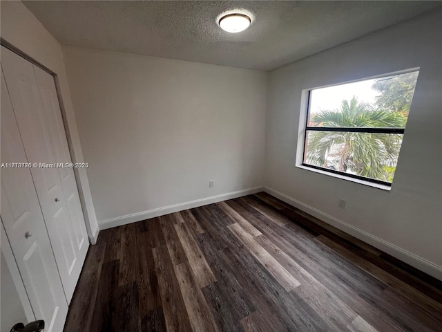 unfurnished bedroom with a closet, dark wood-type flooring, and a textured ceiling