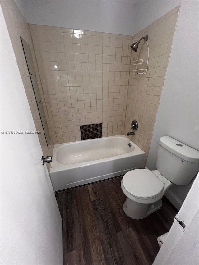 bathroom with tiled shower / bath combo, toilet, and wood-type flooring