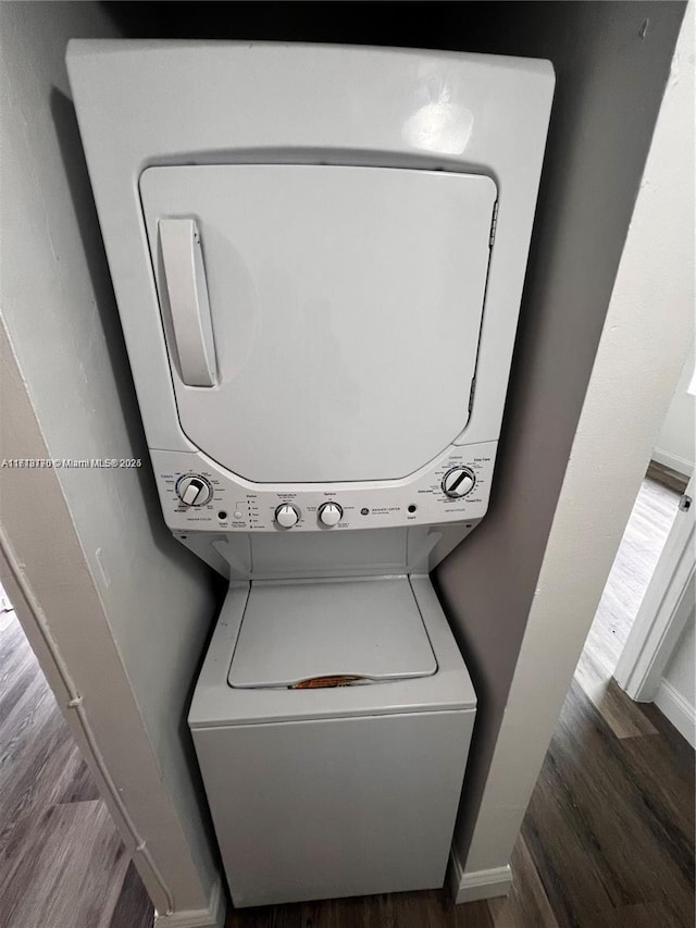 laundry room with stacked washing maching and dryer and hardwood / wood-style flooring