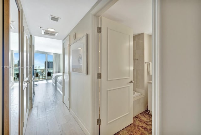 corridor with light hardwood / wood-style floors and a wall of windows