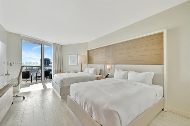 bedroom with expansive windows, access to outside, and light hardwood / wood-style flooring