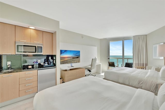 bedroom featuring refrigerator, access to exterior, a wall of windows, and light hardwood / wood-style flooring