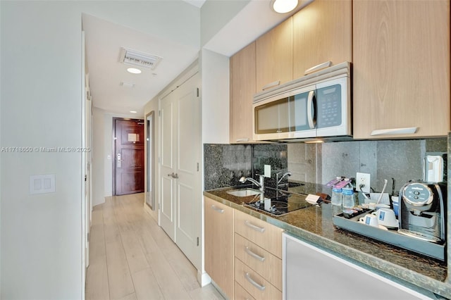 kitchen featuring light brown cabinetry, backsplash, black electric cooktop, sink, and light hardwood / wood-style flooring