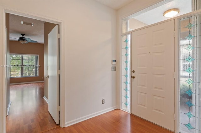 foyer entrance with ceiling fan, light wood-type flooring, and a textured ceiling