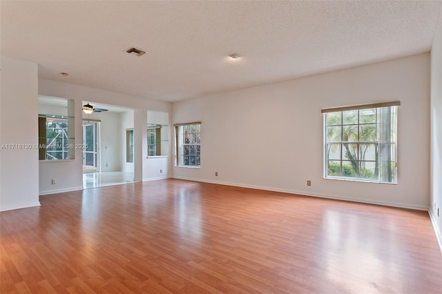 unfurnished room featuring ceiling fan, light hardwood / wood-style flooring, and a textured ceiling