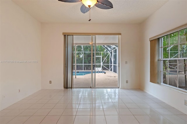 empty room with ceiling fan, light tile patterned floors, and a textured ceiling