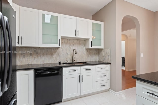 kitchen with black appliances, white cabinets, light tile patterned floors, and sink