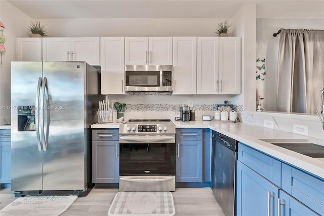 kitchen featuring white cabinetry, stainless steel appliances, blue cabinetry, and backsplash