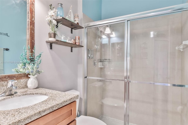 bathroom with vanity, a shower with shower door, and toilet