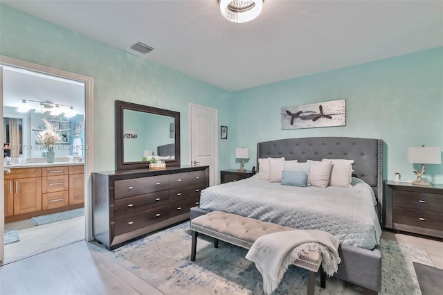 bedroom featuring ensuite bathroom and light wood-type flooring