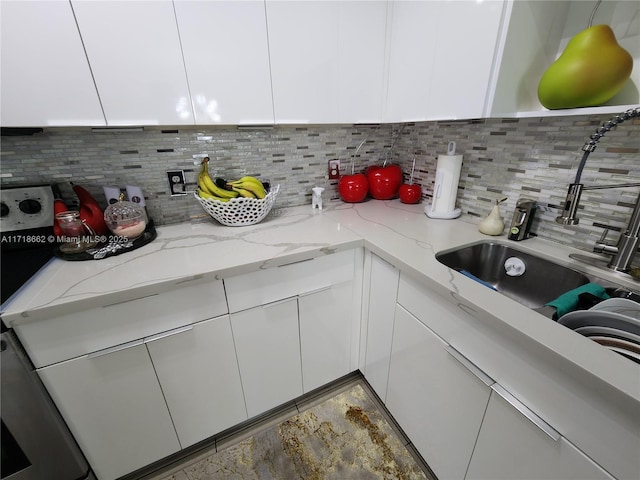 kitchen with decorative backsplash, white cabinetry, and light stone counters