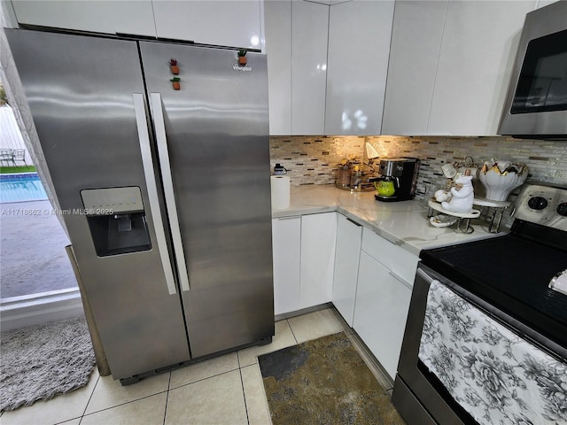 kitchen with white cabinets, appliances with stainless steel finishes, decorative backsplash, and light tile patterned flooring