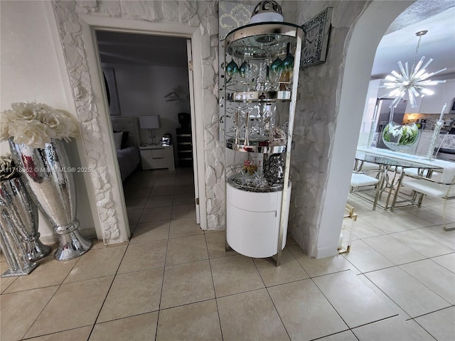 hallway featuring light tile patterned flooring and a chandelier