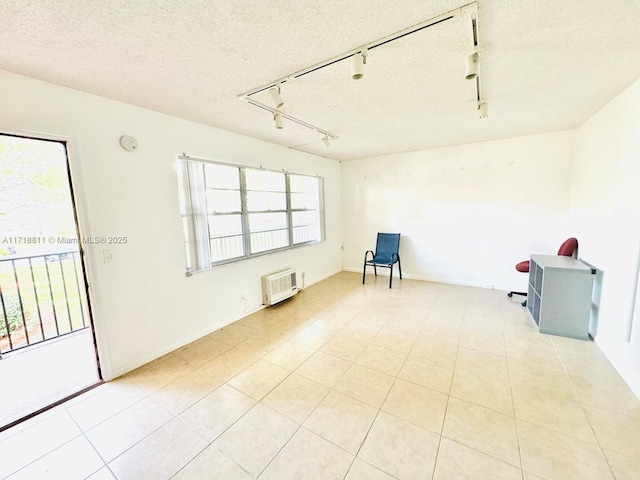 spare room featuring a textured ceiling, rail lighting, light tile patterned floors, and an AC wall unit