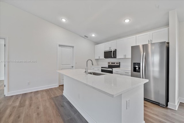 kitchen featuring an island with sink, stainless steel appliances, light stone countertops, white cabinets, and sink