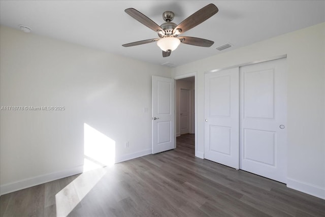 unfurnished bedroom featuring a closet, dark hardwood / wood-style floors, and ceiling fan