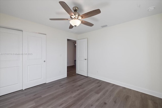 unfurnished bedroom featuring ceiling fan, a closet, and dark hardwood / wood-style flooring