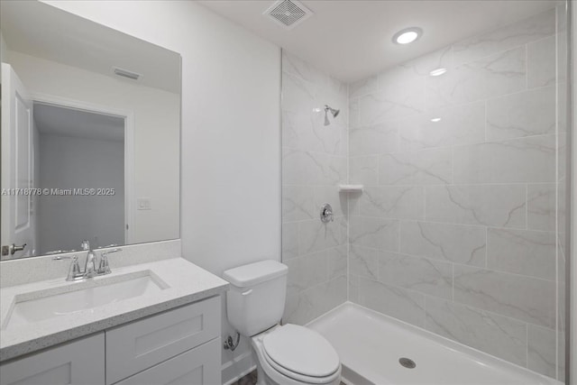 bathroom with toilet, vanity, and a tile shower