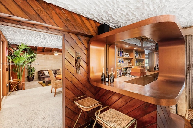 bar featuring wooden walls, carpet floors, and vaulted ceiling