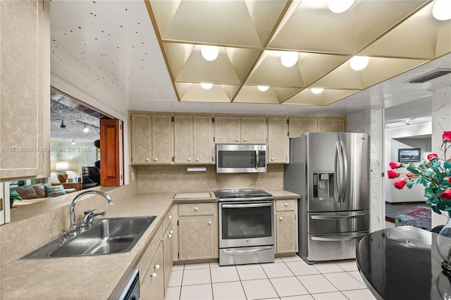 kitchen featuring backsplash, sink, light tile patterned floors, light brown cabinetry, and stainless steel appliances