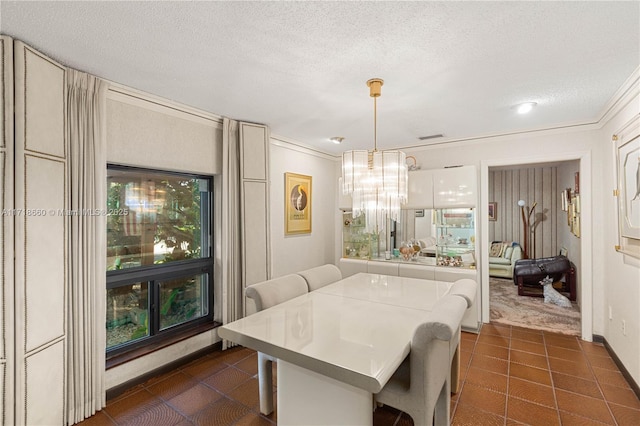 tiled dining room with a textured ceiling, crown molding, and a chandelier