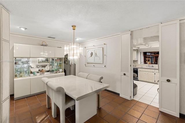 kitchen with dark tile patterned floors, sink, pendant lighting, white cabinets, and a breakfast bar area