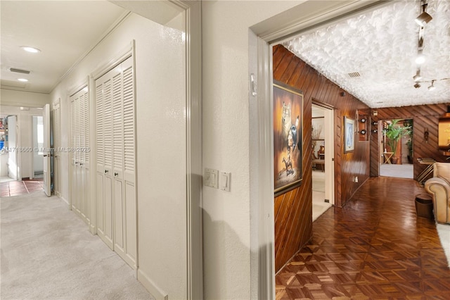 corridor with parquet floors, ornamental molding, and wood walls