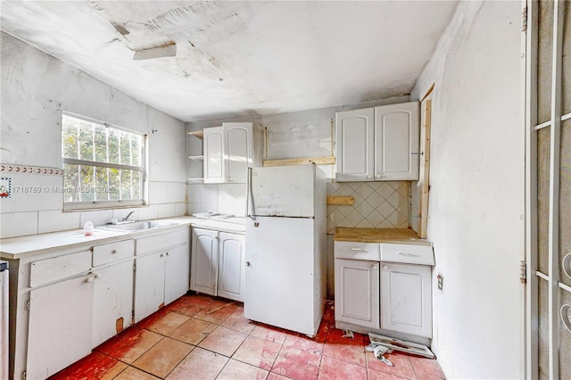 kitchen with white cabinets, decorative backsplash, sink, and white fridge