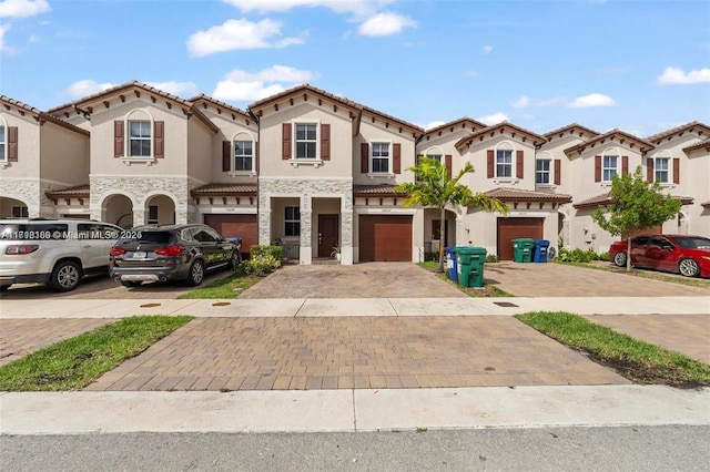 view of front of property with driveway, stone siding, an attached garage, and stucco siding