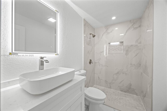 bathroom with vanity, toilet, and tiled shower