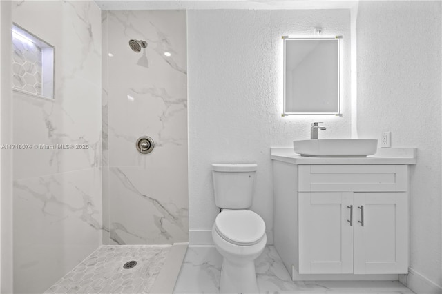 bathroom with a tile shower, vanity, and toilet