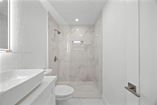 bathroom featuring vanity, toilet, and tiled shower