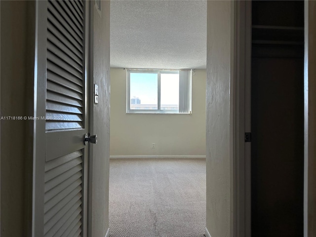 hallway featuring light carpet and a textured ceiling