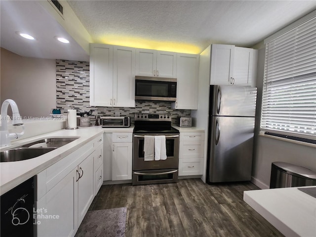 kitchen with white cabinets, sink, dark hardwood / wood-style floors, appliances with stainless steel finishes, and tasteful backsplash