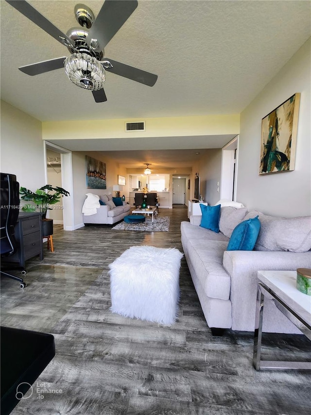 living room featuring ceiling fan, dark hardwood / wood-style flooring, and a textured ceiling